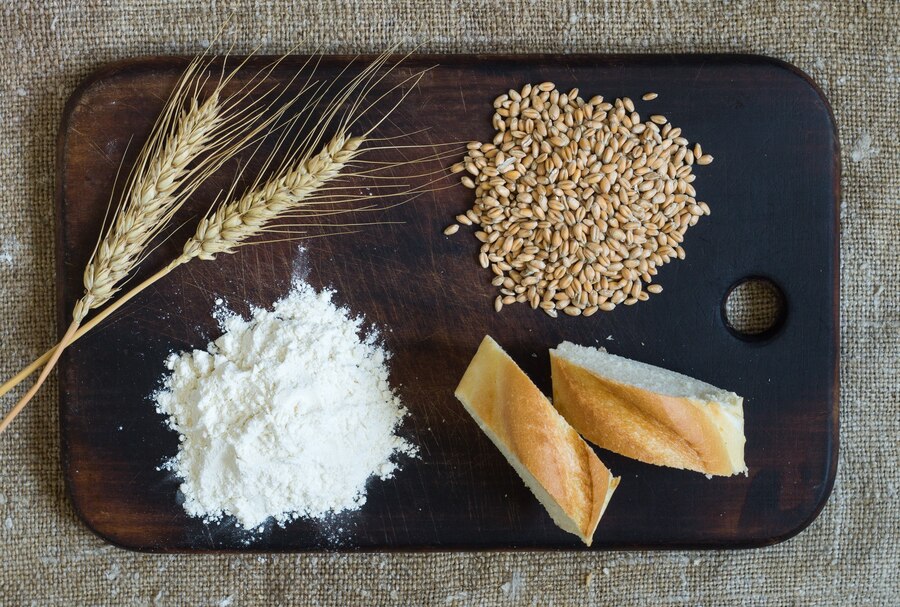 wheat-ears-grains-flour-sliced-bread-kitchen-board-sacking-background-top